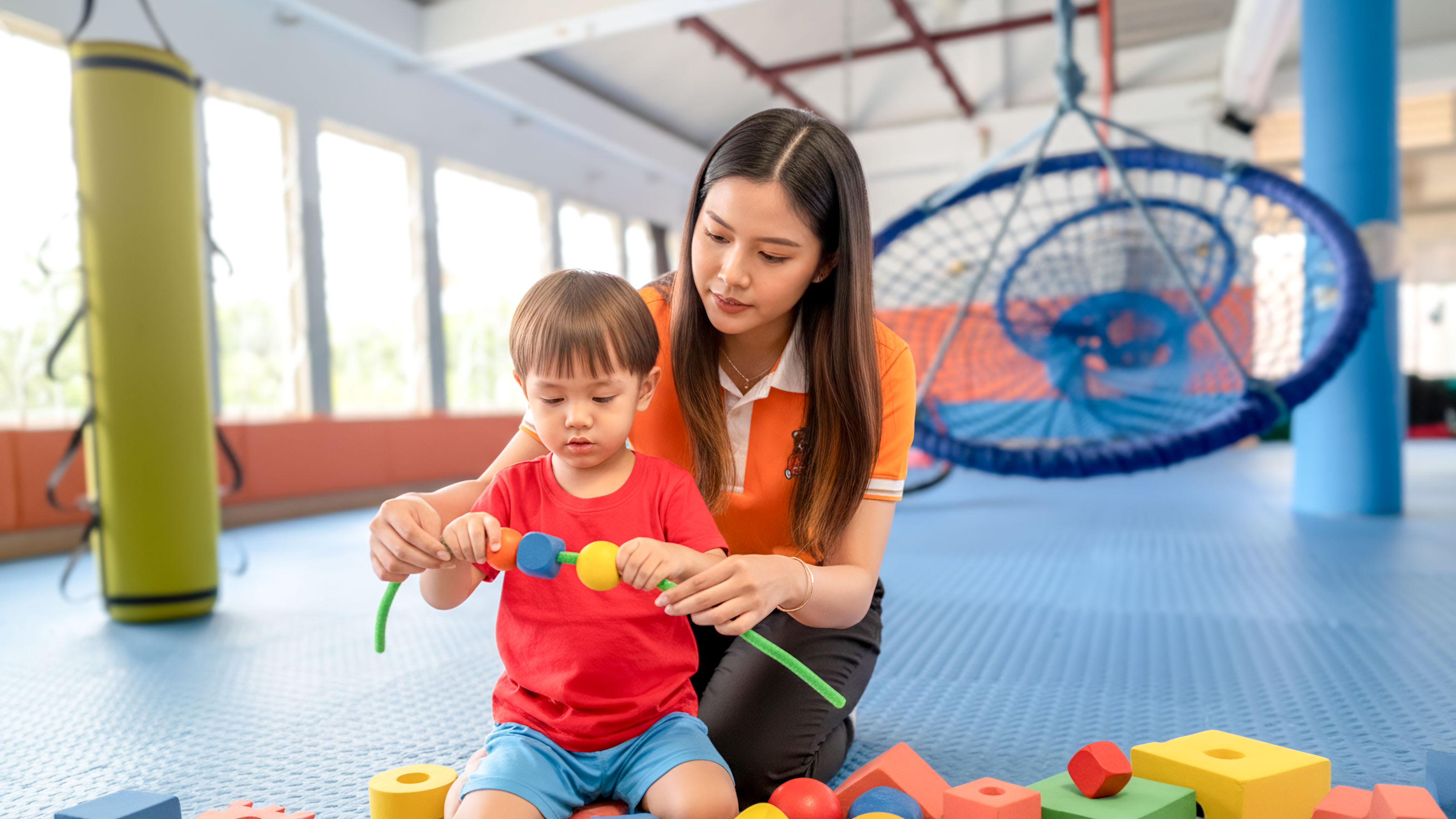 A special education teacher helping a child develop fine motor skills through play at MLPIS