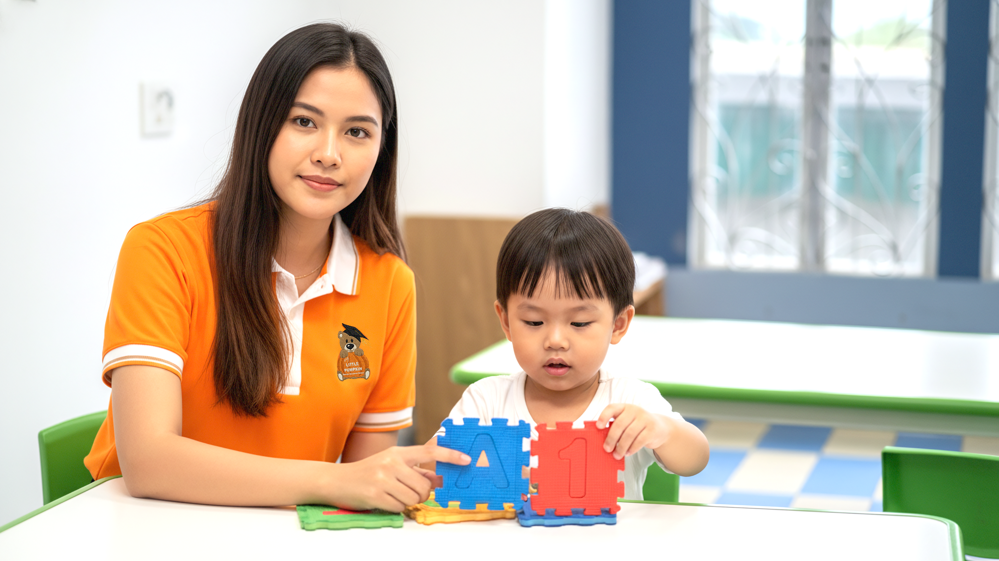 A caring teacher helping a young child with learning activities at My Little Pumpkin Special Education School in Cambodia